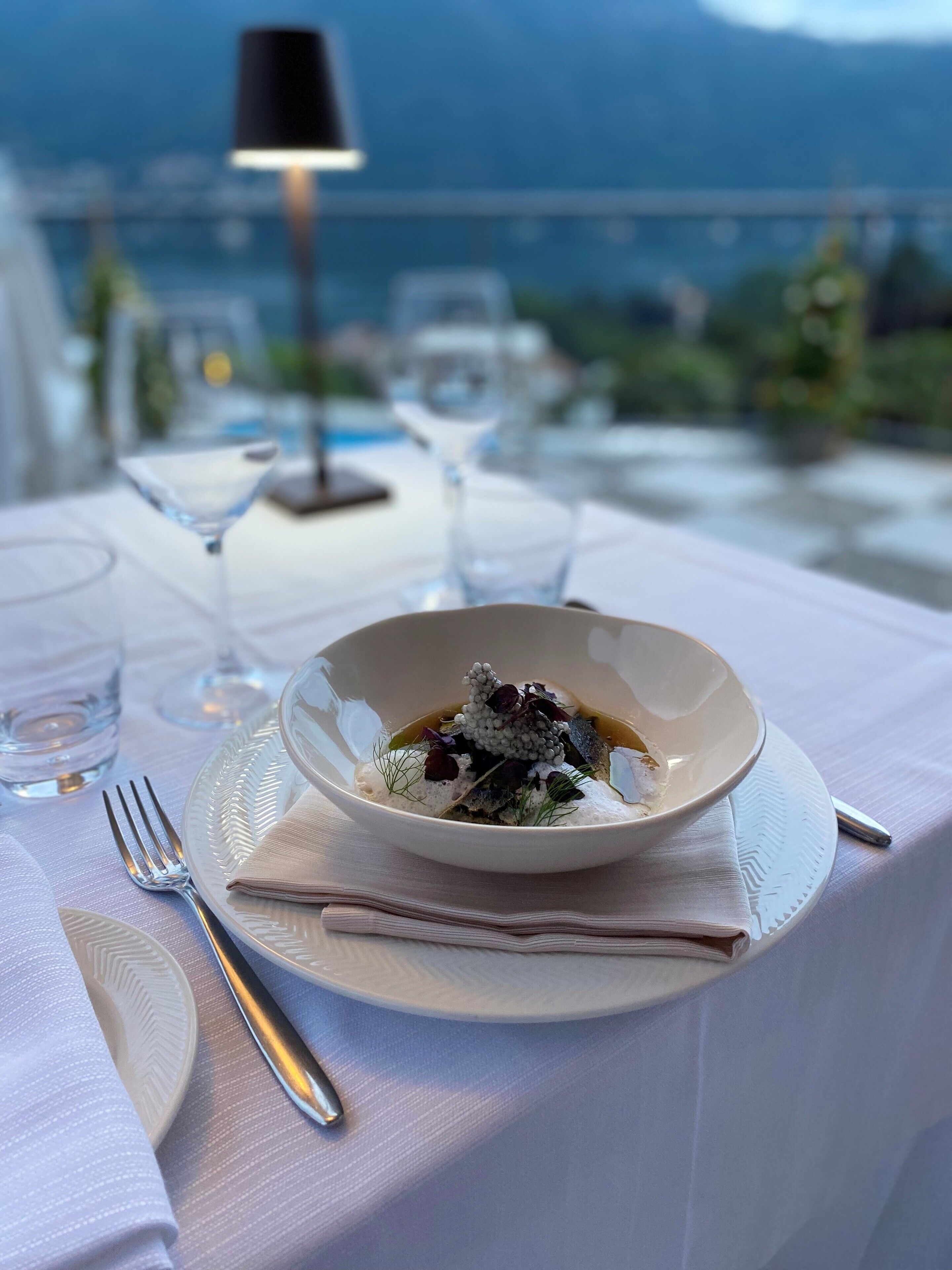 Ein Tisch ist für eine Mahlzeit gedeckt, mit einer Schüssel Essen, einer Gabel und einem Weinglas.