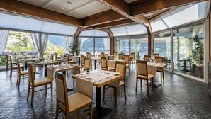 A restaurant with wooden beams, large windows, and a tiled floor.
