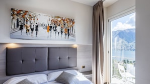 A modern bedroom with a large bed, a headboard, and a painting above it.