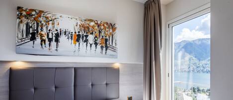 A modern bedroom with a large bed, a headboard, and a painting above it.