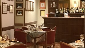 A restaurant with a bar area, framed pictures on the walls, and a polished stone floor.