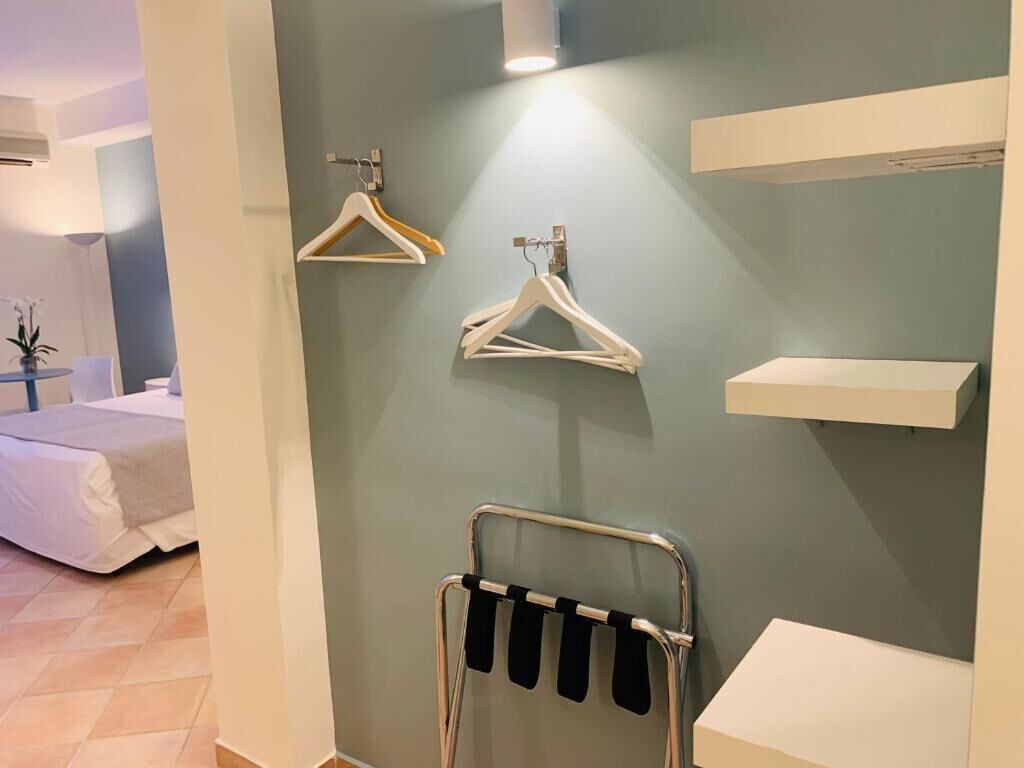 Una habitación de hotel con cama, perchero en la pared y perchero para ropa.