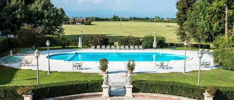 Una piscina al aire libre, sombrillas, tumbonas