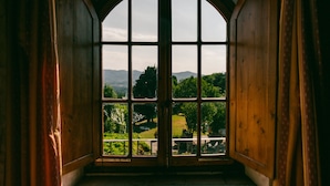 Una habitación con un amplio ventanal que ofrece vistas a un paisaje verde y montañas distantes.