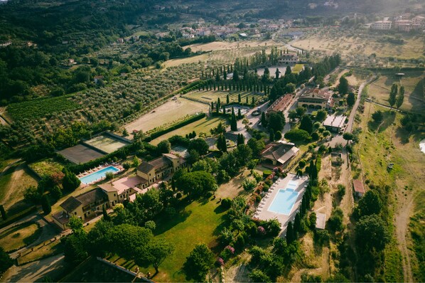 An aerial view of a resort with multiple swimming pools, landscaped gardens, and a variety of buildings. - Hotel Fattoria degli Usignoli (Reggello)