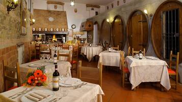 Un restaurante con varias mesas preparadas para comer, una chimenea de ladrillo y puertas de barricas de madera.