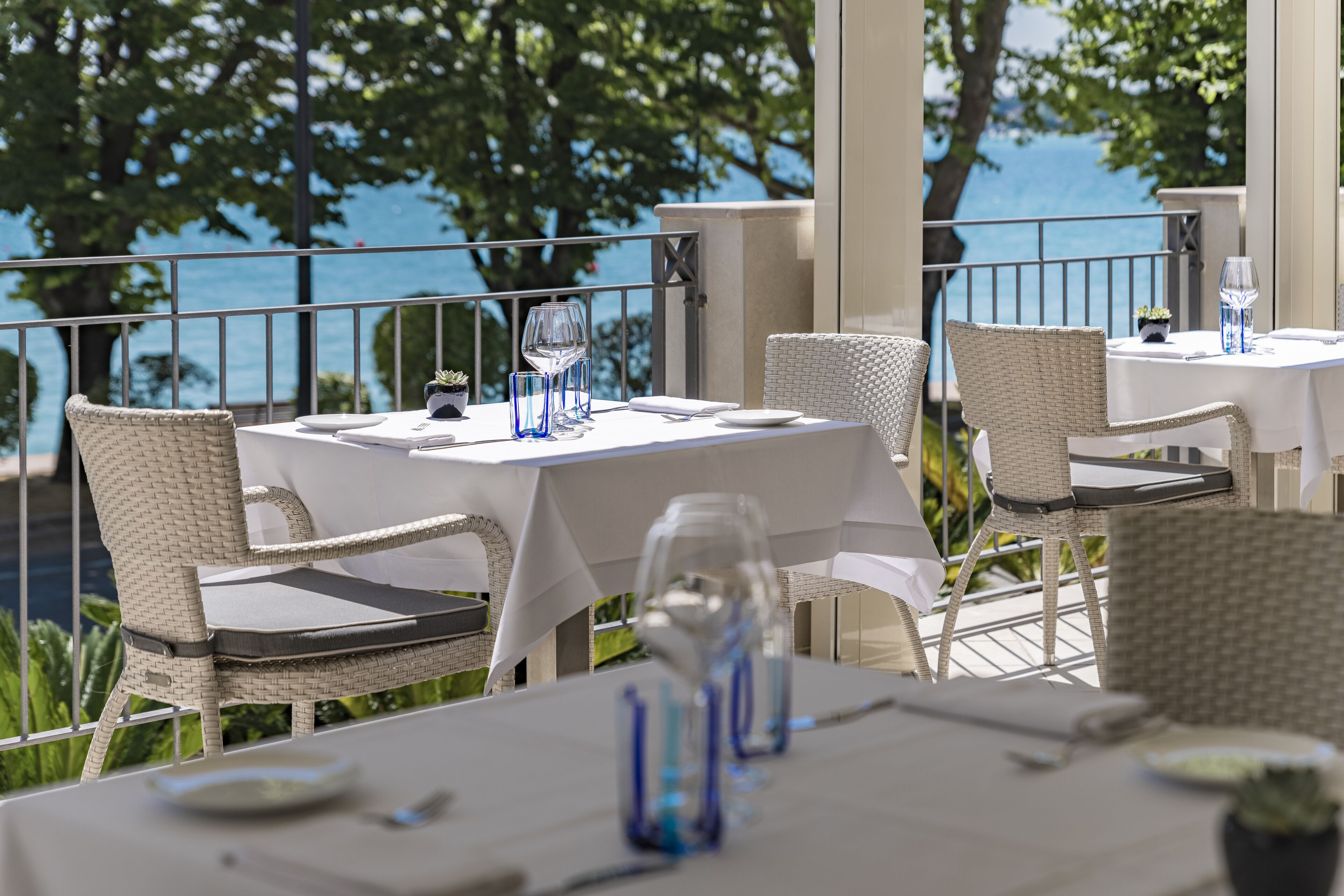 A terrace with tables set for dining, overlooking a body of water.