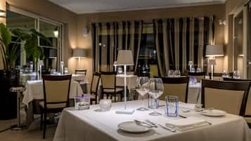 A dining area with a table set for two, featuring a white tablecloth, clear glassware, and a candle centerpiece.