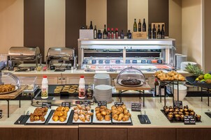 Un bufé de desayuno con diversos pasteles, platos calientes y bebidas.