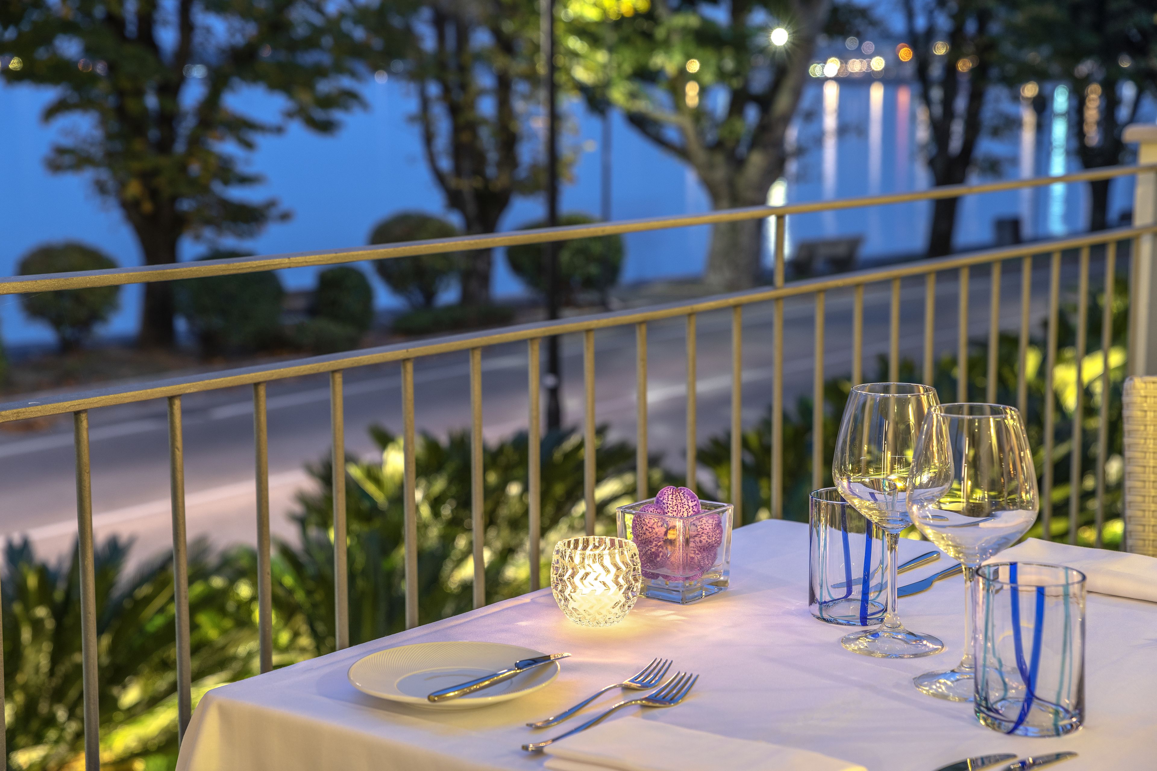 A table set for a meal with wine glasses, a candle, and cutlery, overlooking a scenic view.