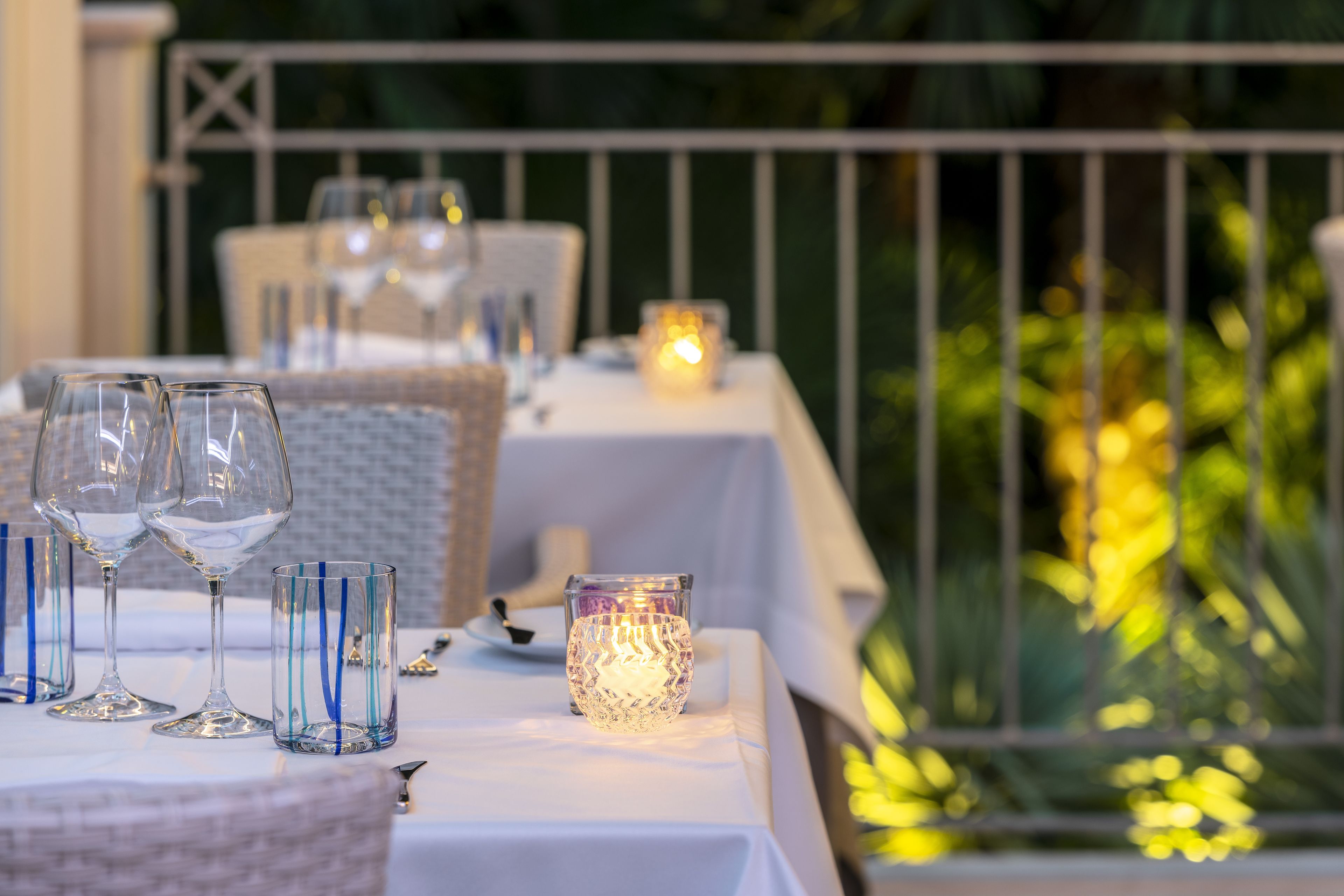 A table set for dining with wine glasses, a candle, and a basket.