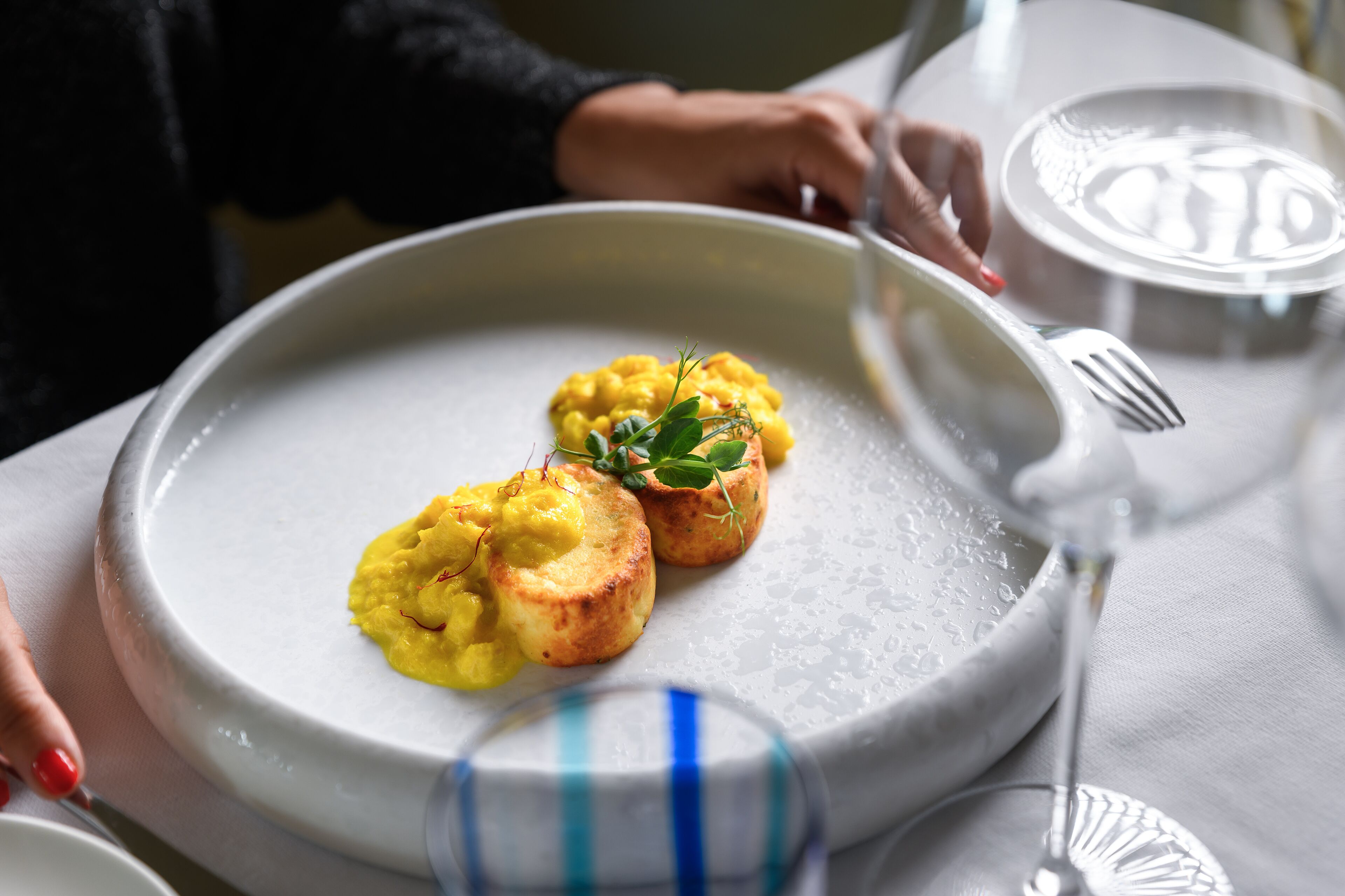 A dining table with a plate of food, a glass of water, and a fork.