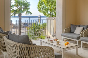 A balcony with wicker furniture, a table with breakfast items, and a view of the sea.