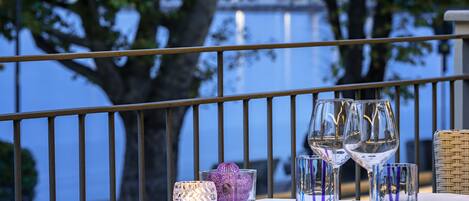 A table set for dining with clear glassware and a candle, overlooking a body of water.
