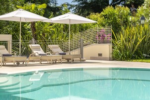 Una piscina al aire libre de temporada, sombrillas