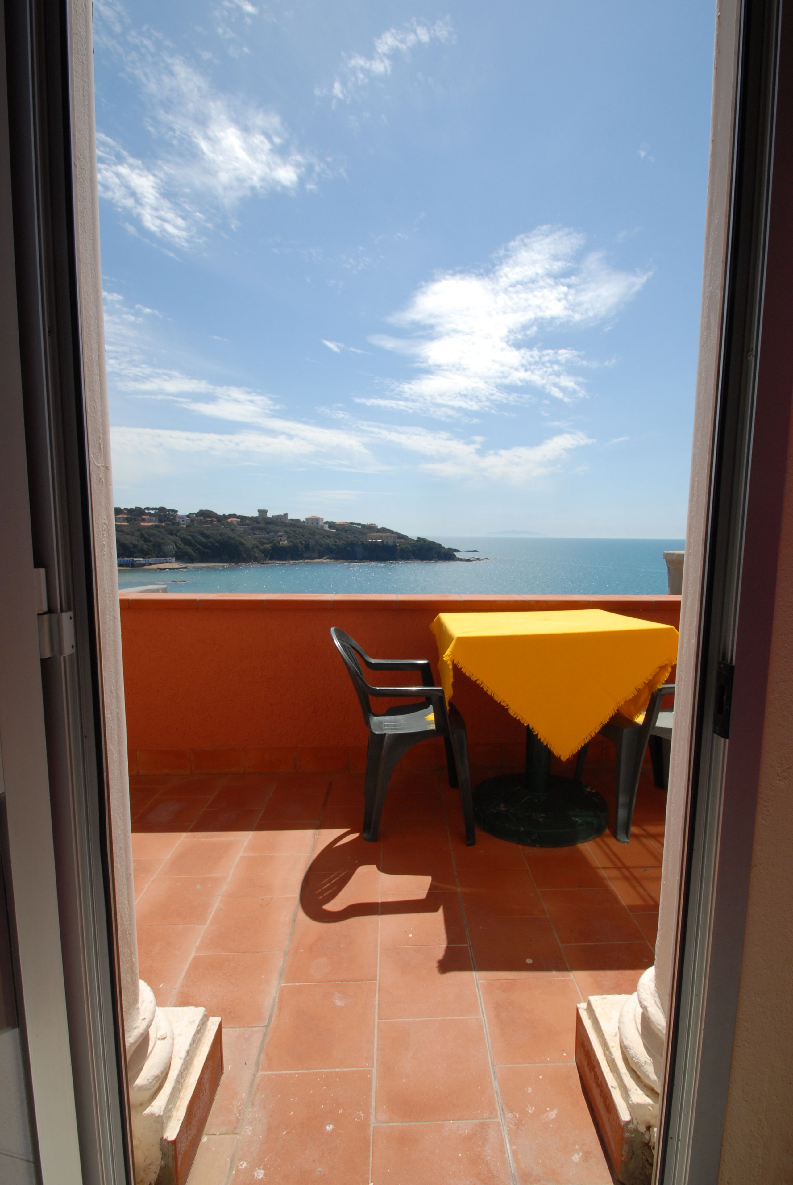 Un balcone con tavolo e sedie, vista sulla costa.