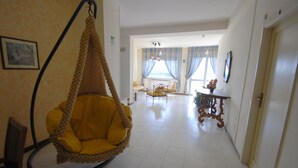 A room with a hanging chair, a bed, a table with flowers, and a chair. - Hotel Ristorante Baia del Sorriso (Rosignano Marittimo)