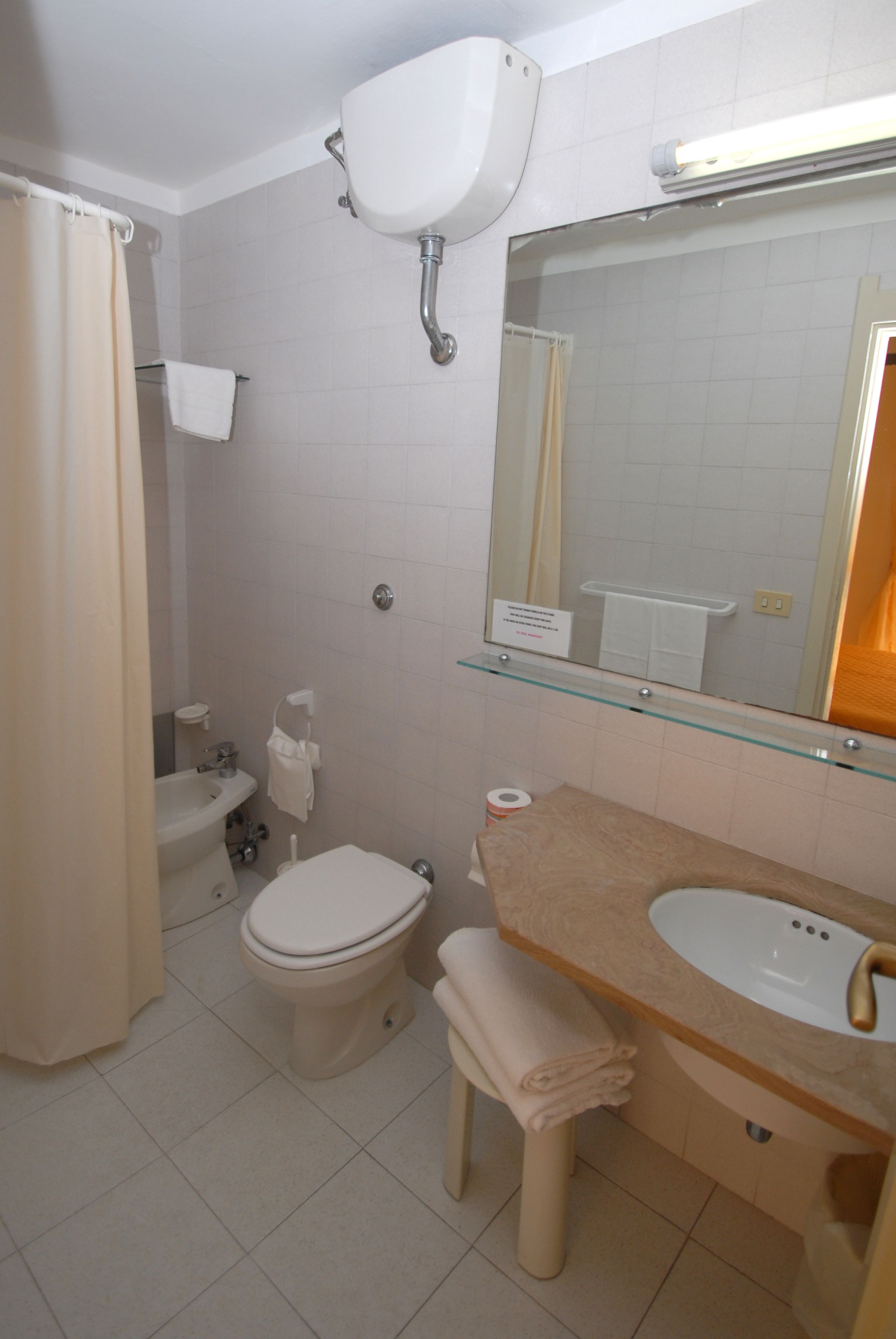 Un baño con inodoro, lavamanos y espejo.