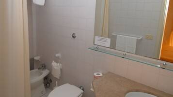 Un baño con inodoro, lavamanos y espejo.
