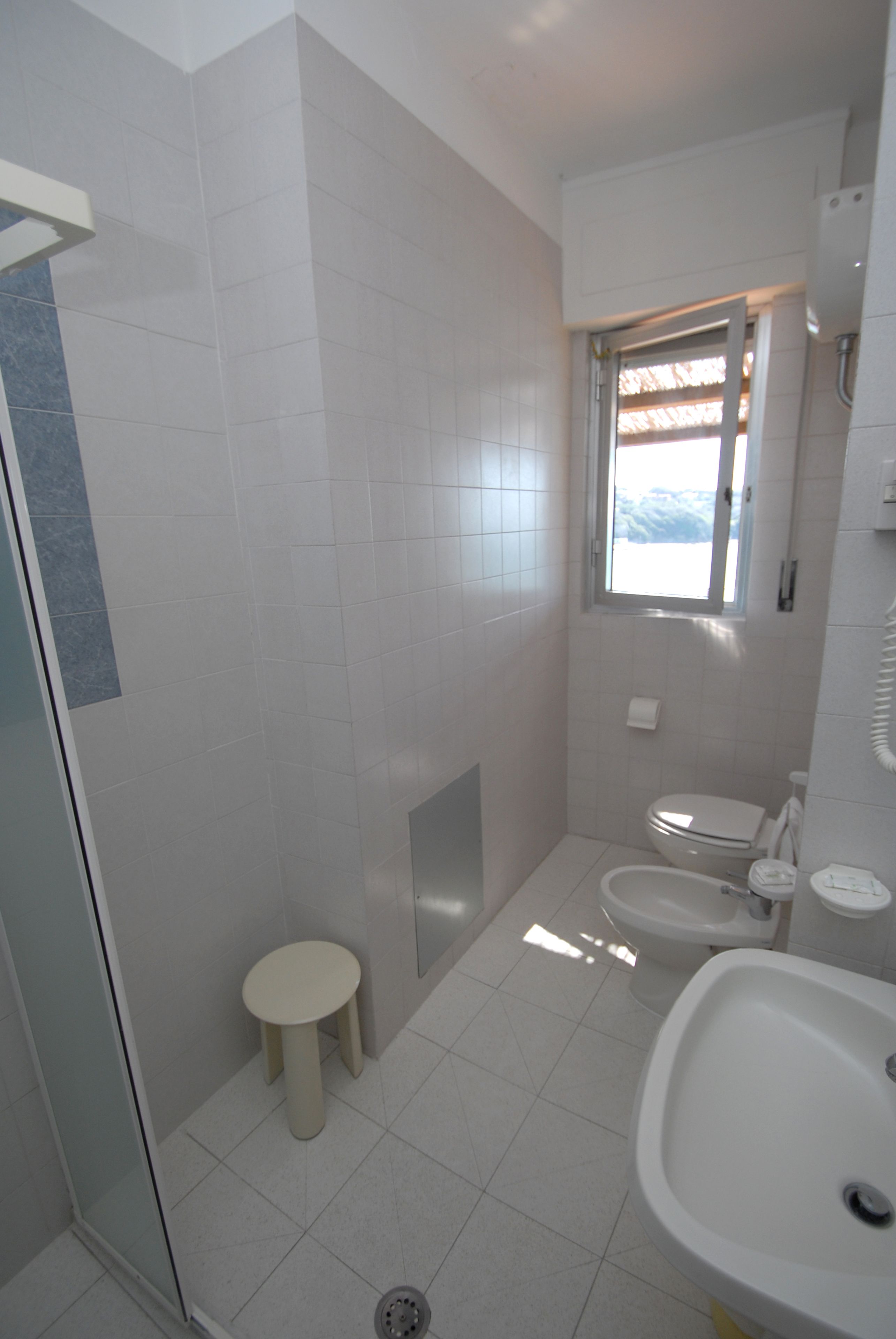 Une salle de bain comprenant des toilettes, un bidet, un lavabo et un petit tabouret.
