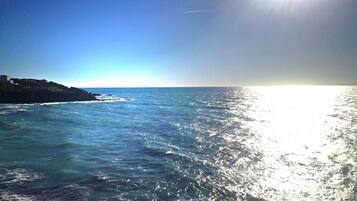 A coastal scene with a clear sky and sunlight reflecting off the water.