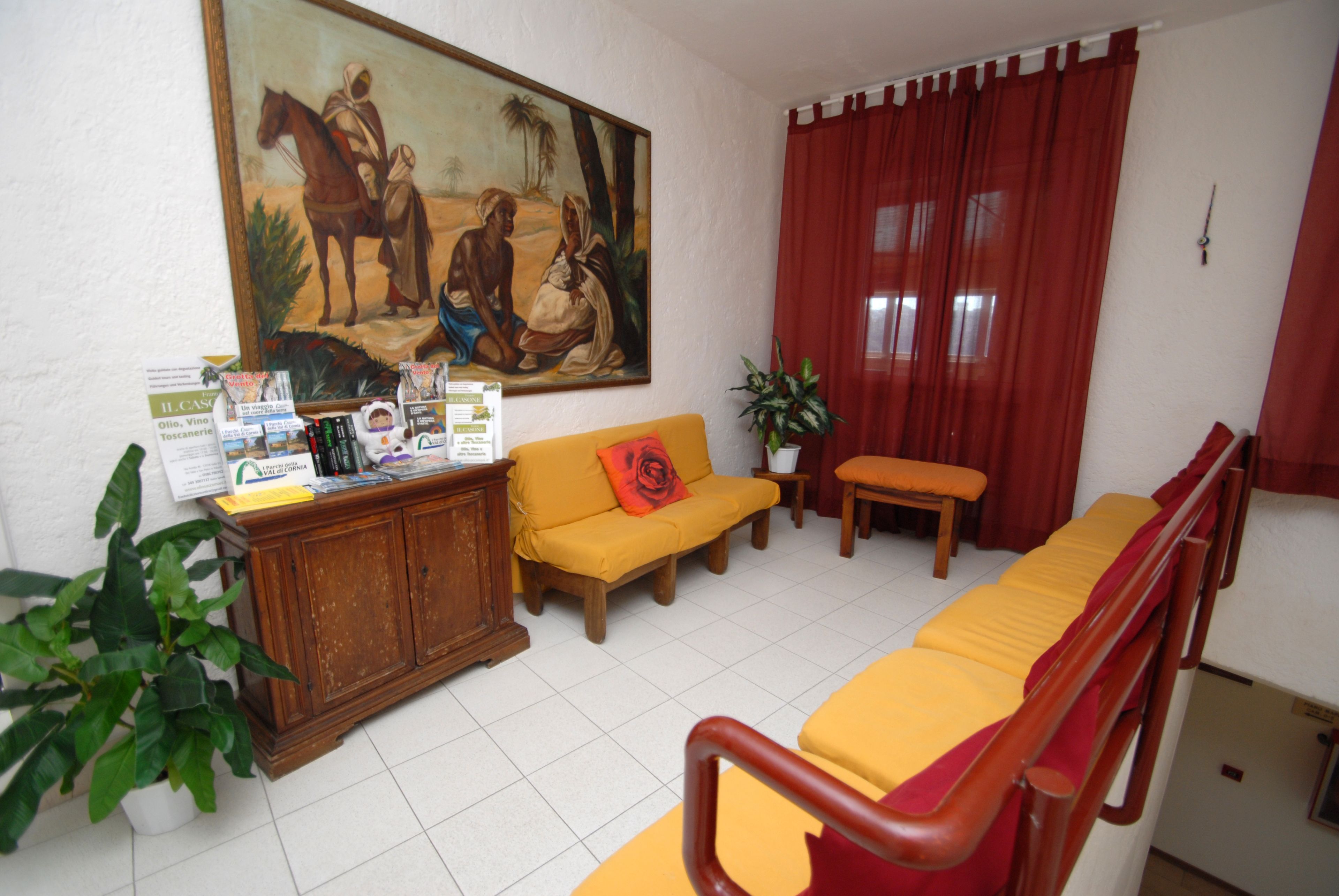 A living room with a sofa, a wooden cabinet, a painting, and a red curtain.