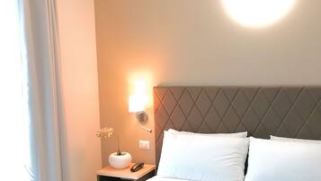 Une chambre d’hôtel avec un grand lit, une table de chevet avec une lampe et un luminaire fixé au mur.