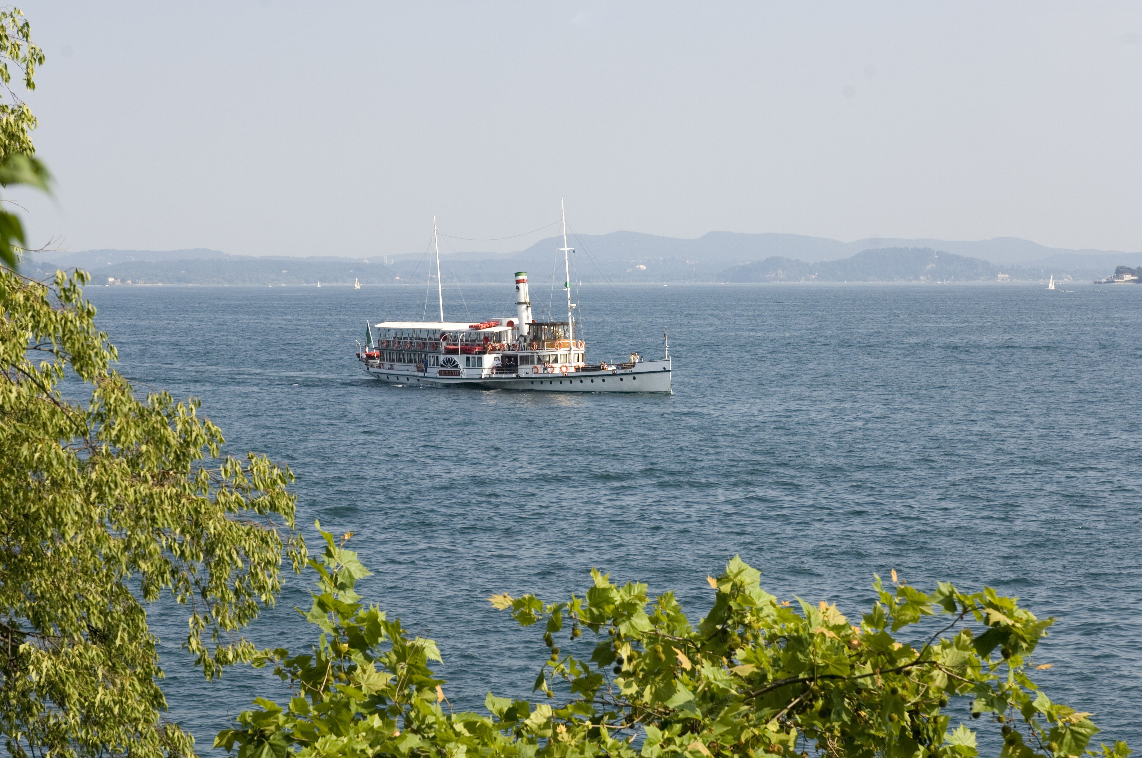 A ferry boat on a calm body of water with a distant shoreline and hills.