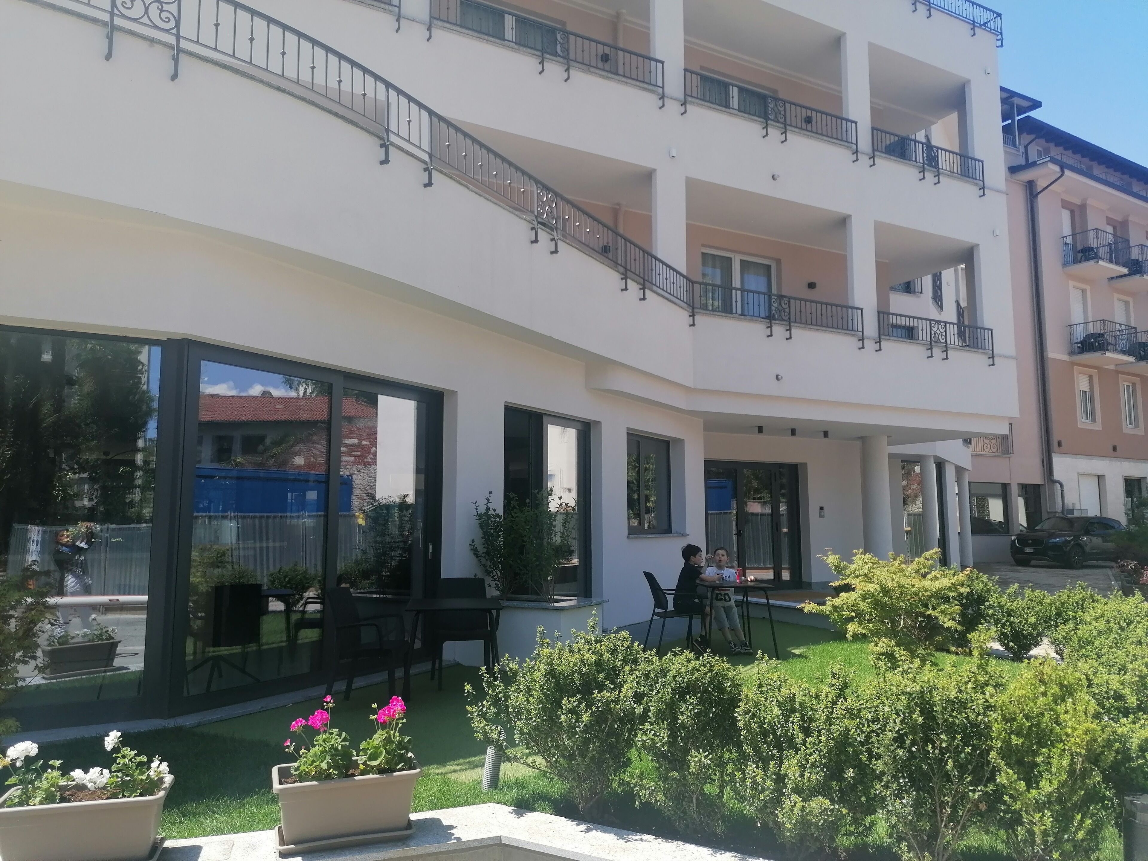 Un immeuble résidentiel à plusieurs étages doté de balcons, de grandes fenêtres et d’espaces extérieurs aménagés pour s’asseoir.
