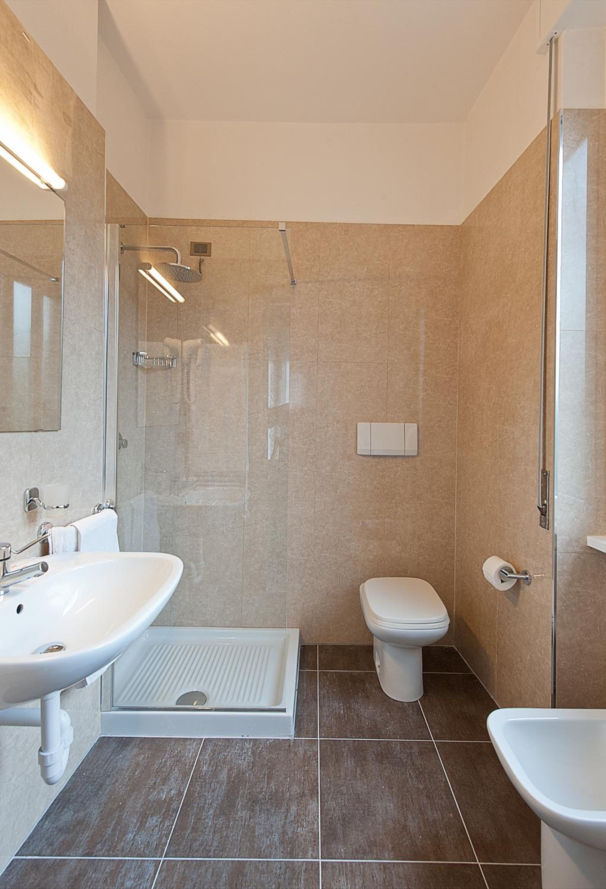 Un baño moderno con cabina de ducha de vidrio, inodoro y dos lavamanos.