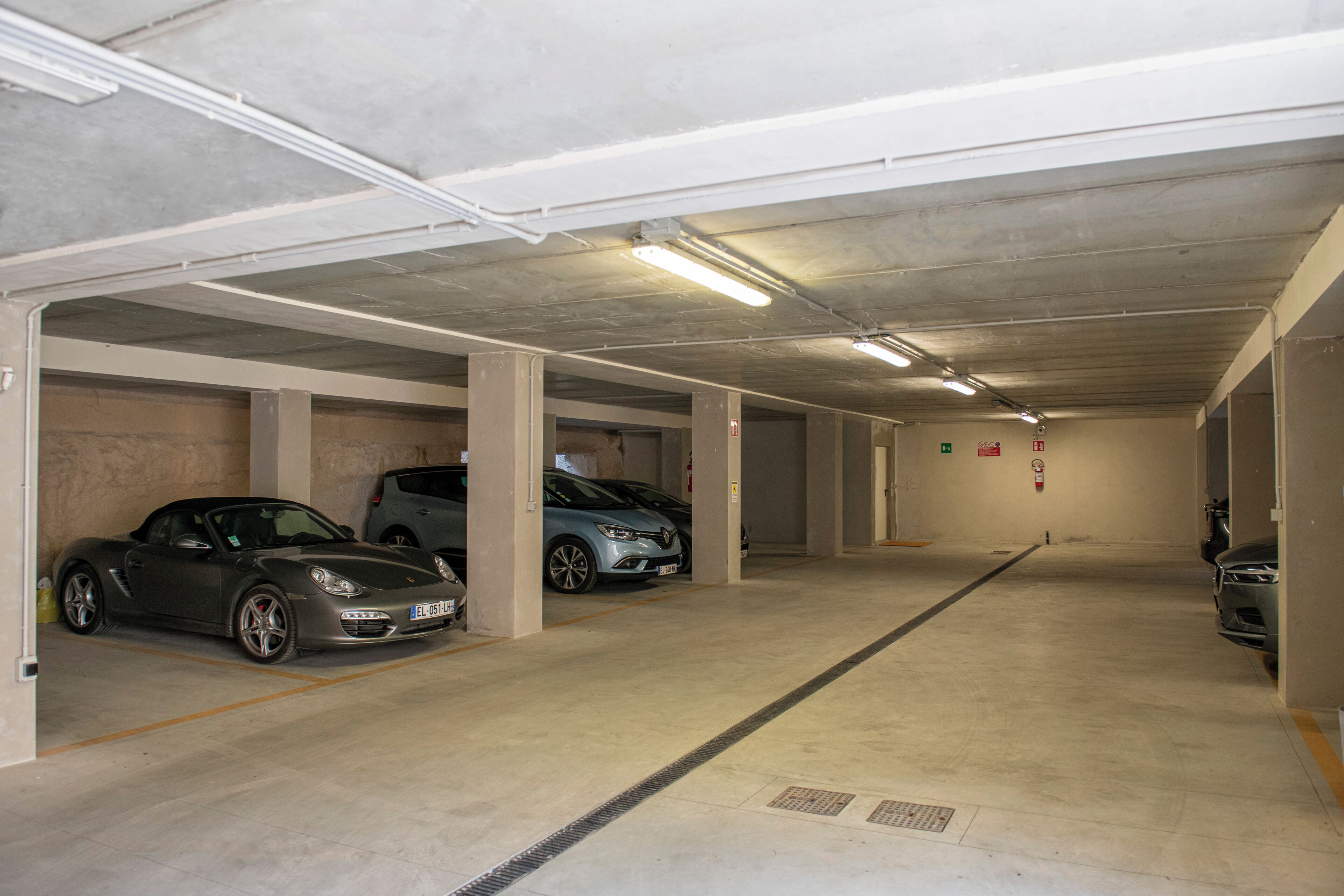 Eine mehrgeschossige Tiefgarage mit Betonpfeilern und Neonbeleuchtung.