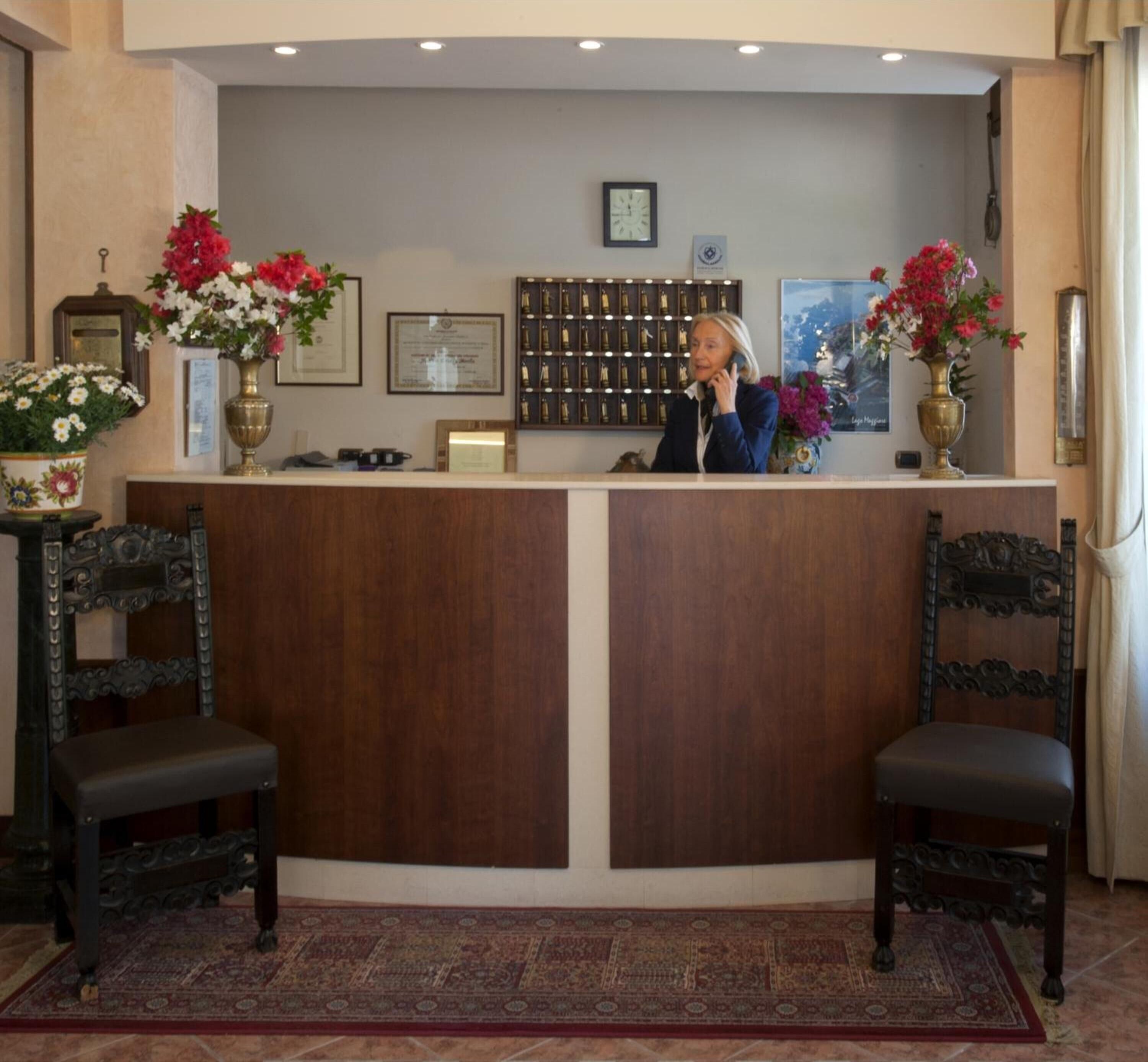 A reception area with a wooden reception desk, two ornate chairs, and a large patterned rug on the floor.