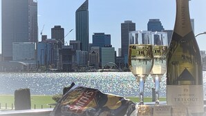 A city skyline with modern buildings and a body of water in the foreground. - The Peninsula Riverside Serviced Apartments (South Perth)