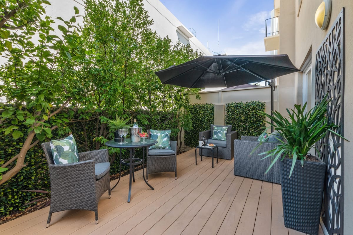 An outdoor patio with wicker furniture, a table, and a potted plant.