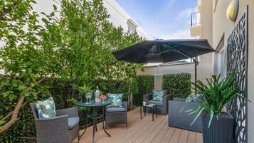 Un patio al aire libre con muebles de mimbre, una mesa y una planta en maceta.