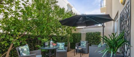 An outdoor patio with wicker furniture, a table, and a potted plant.