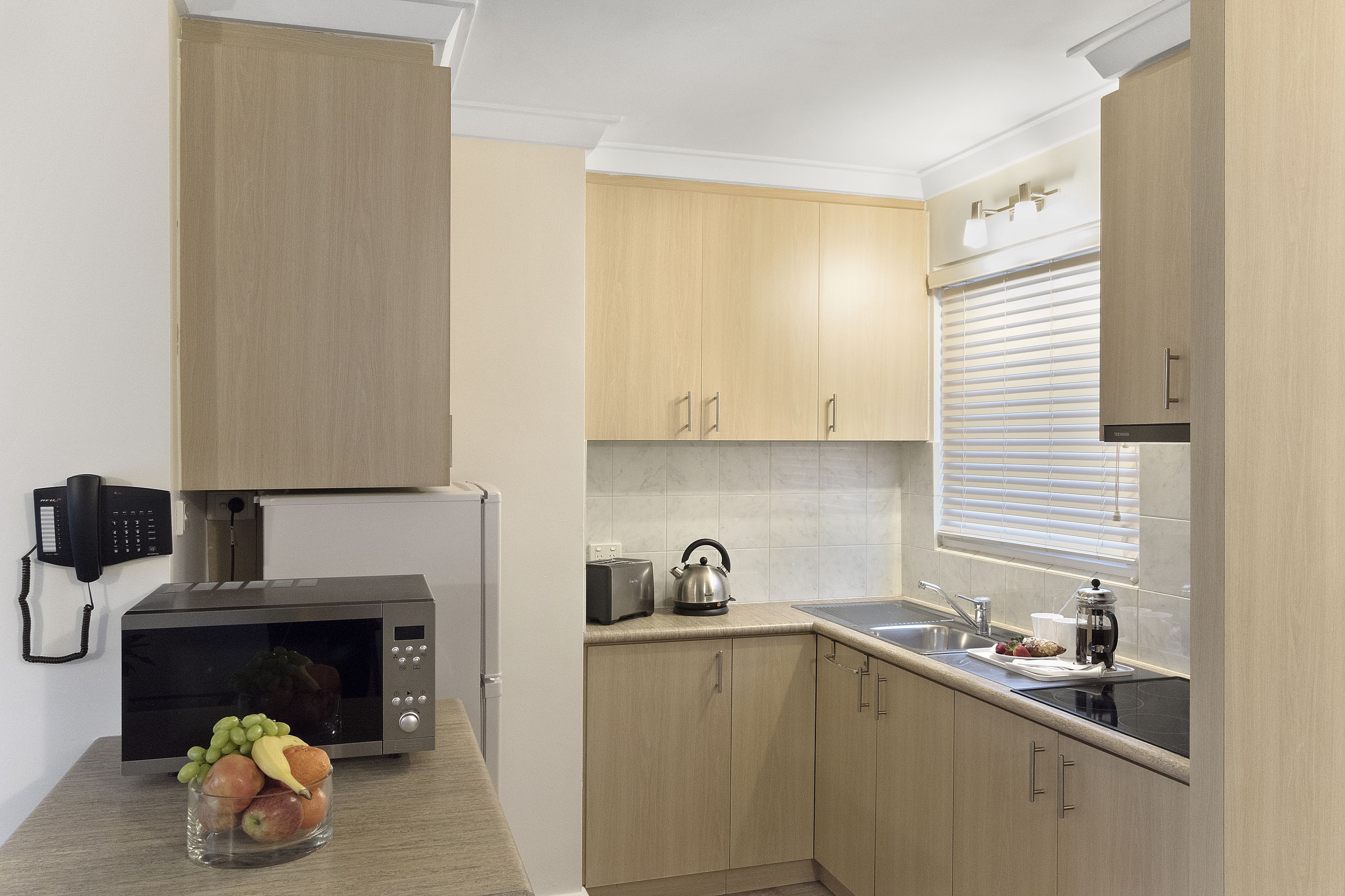 Una cocina moderna con armarios de madera, microondas, tostadora y hervidor.