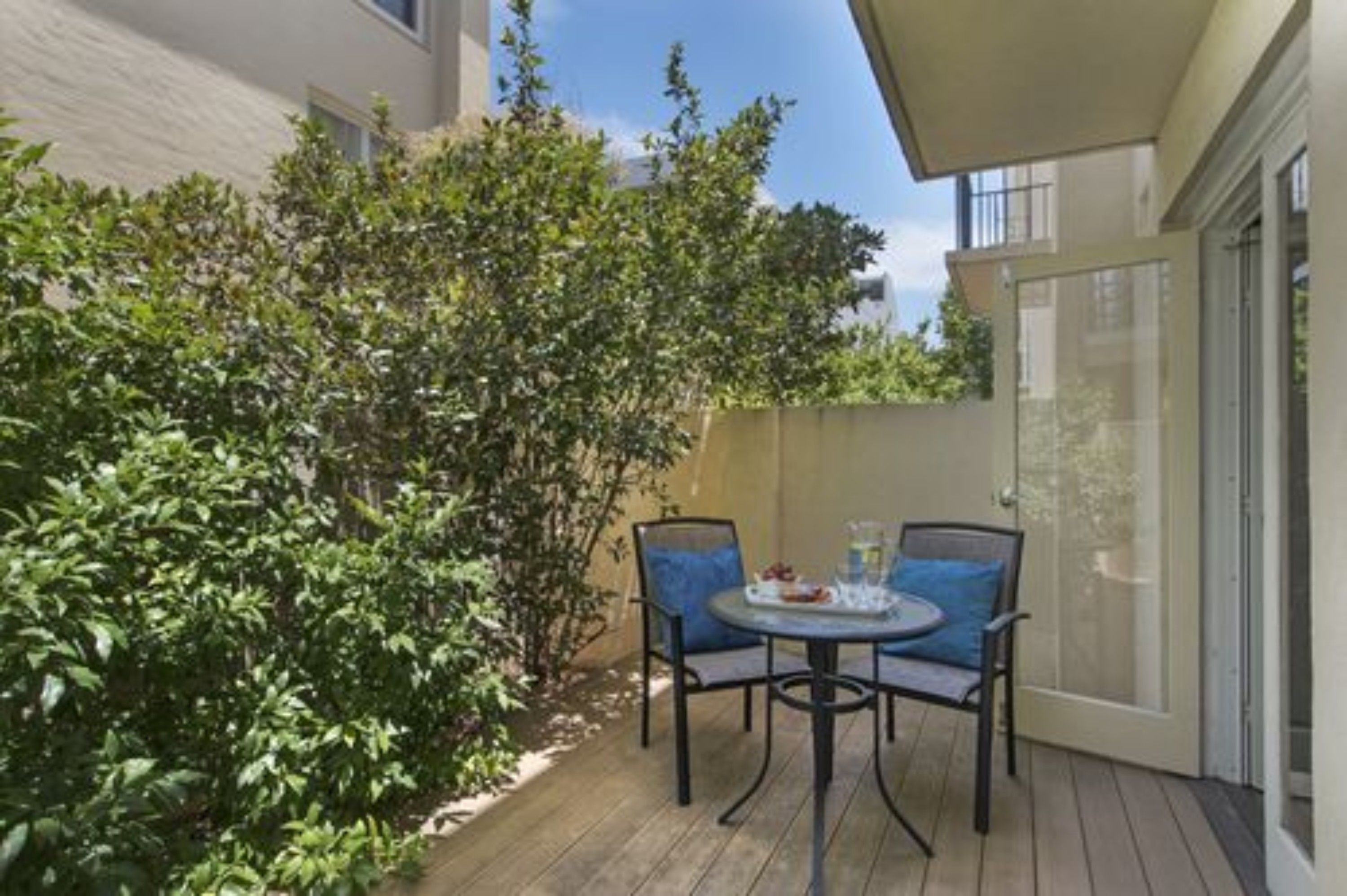 A patio with a table and chairs, surrounded by greenery.