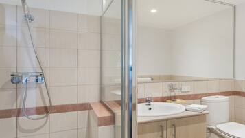 Un baño moderno con cabina de ducha de vidrio, un lavamanos y un inodoro.