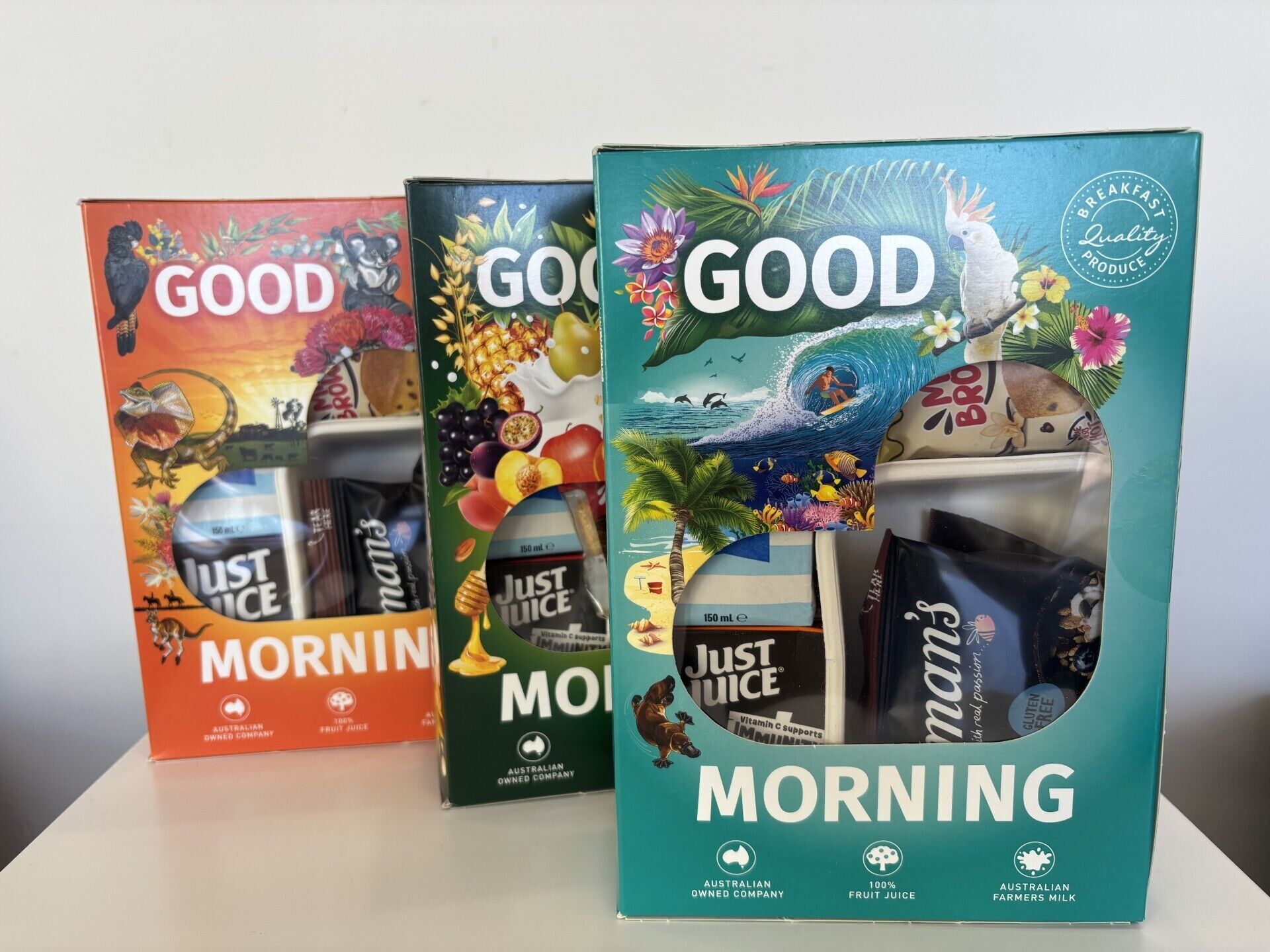 Three Just Juice Morning boxes with tropical and oceanic designs.