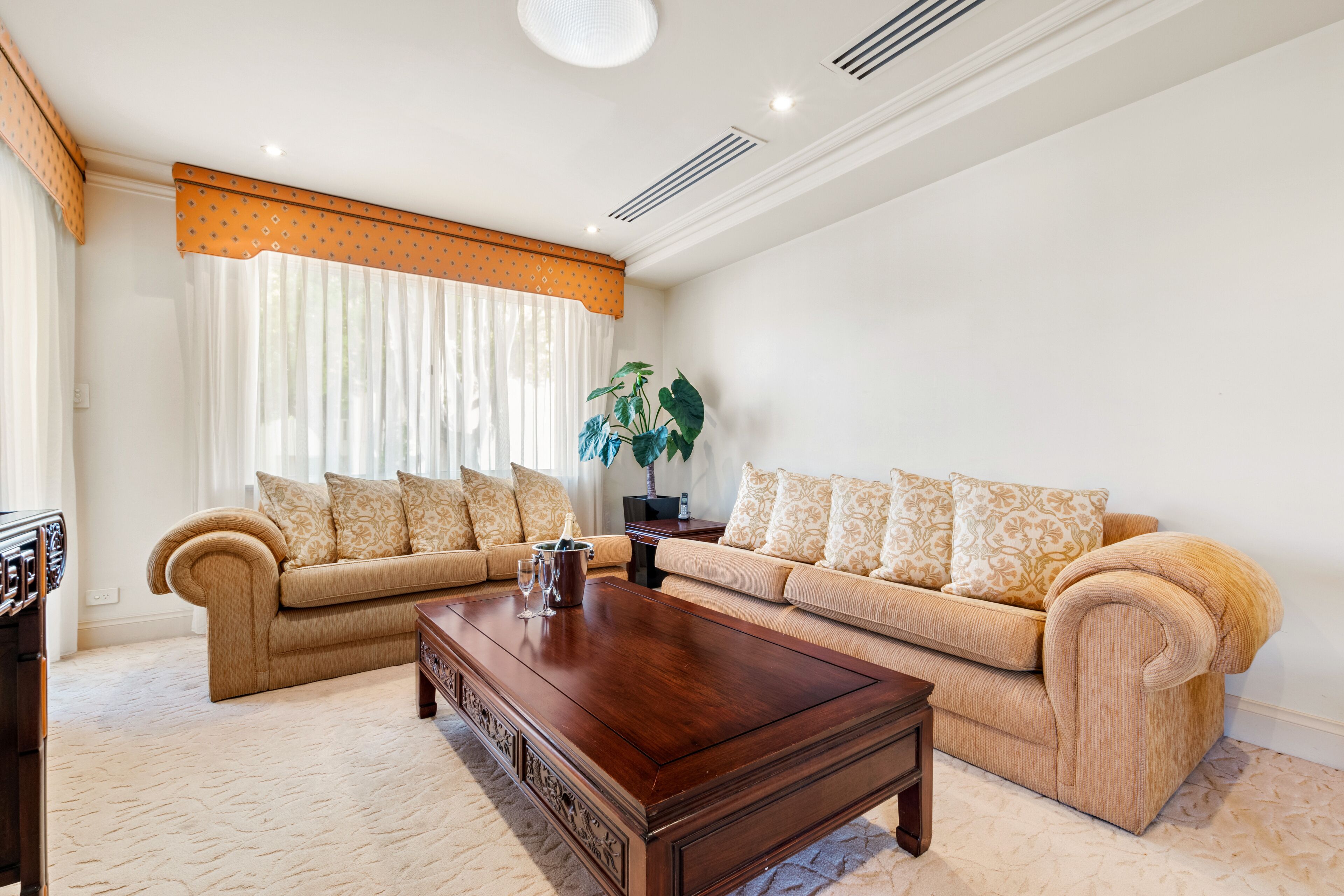 A living room with two beige sofas, a wooden coffee table, and a large window with curtains.