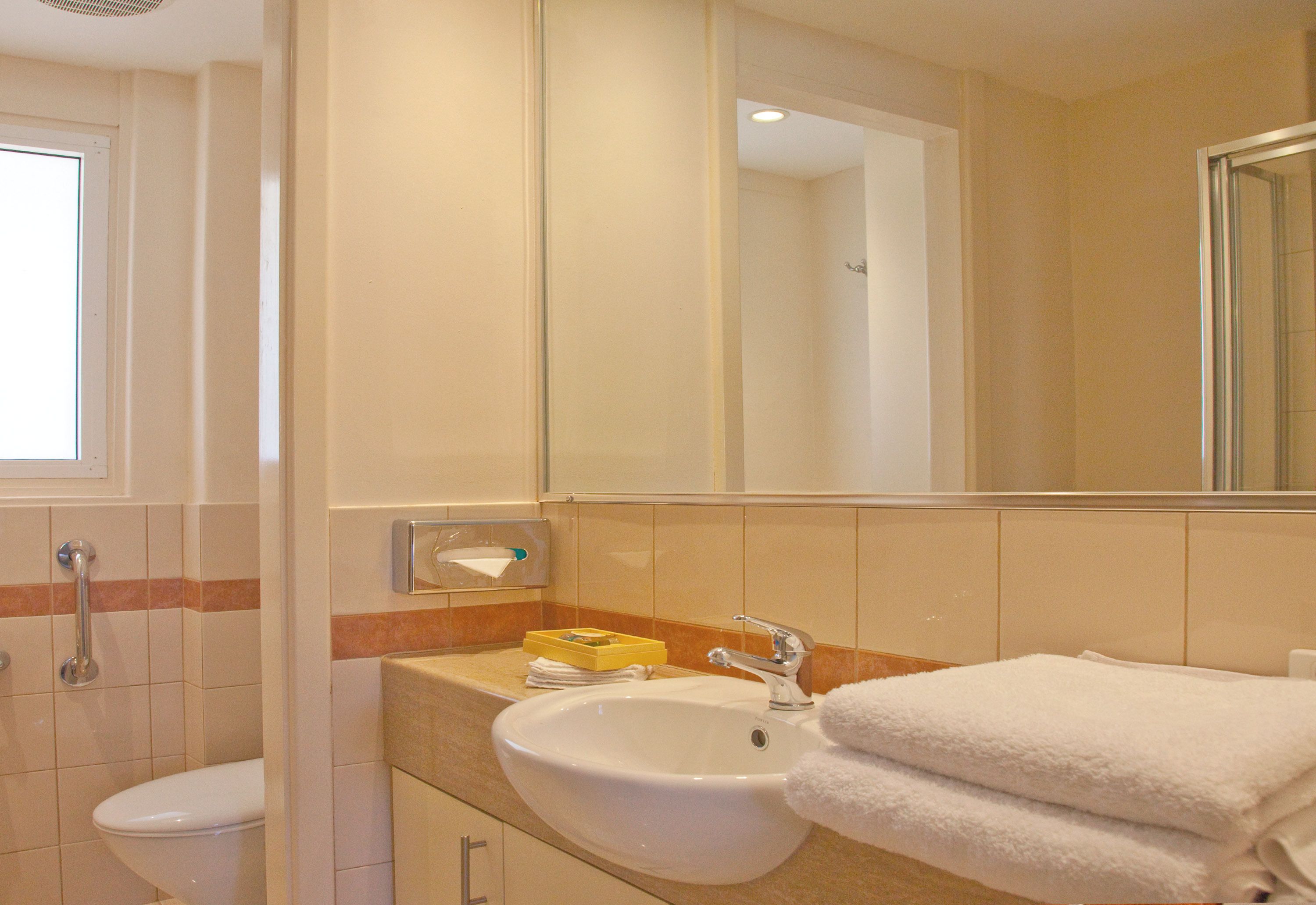Een badkamer met een wastafel, spiegel en toilet.