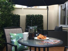 Una mesa redonda de vidrio con un plato de comida, una cafetera y una taza.