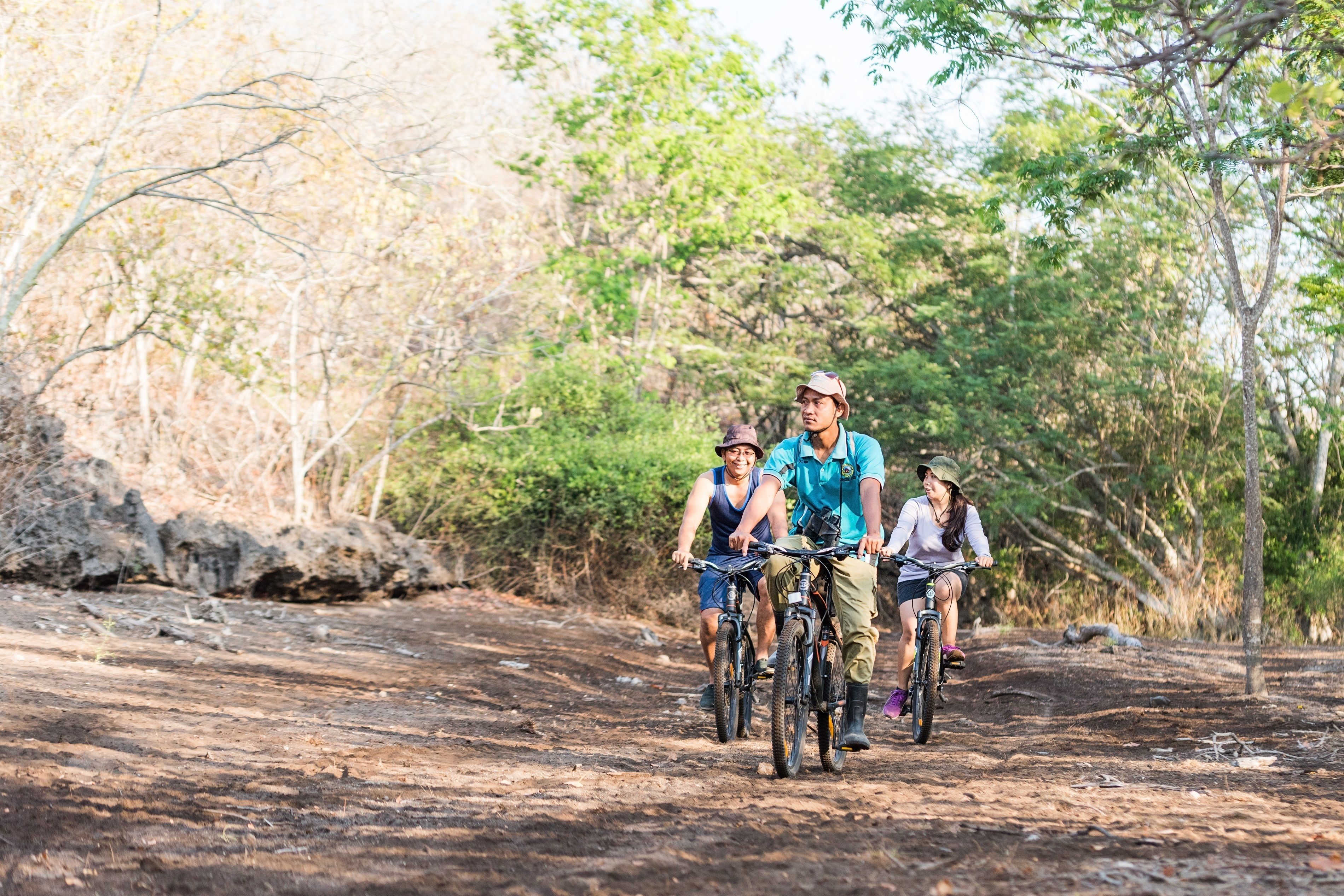 Un grupo de personas montando bicicletas por un sendero de tierra rodeado de árboles.