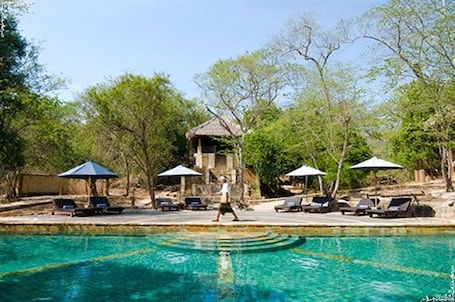 Una piscina al aire libre, sillones reclinables de piscina