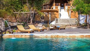 Un espace piscine avec des chaises longues et un mur en pierre.