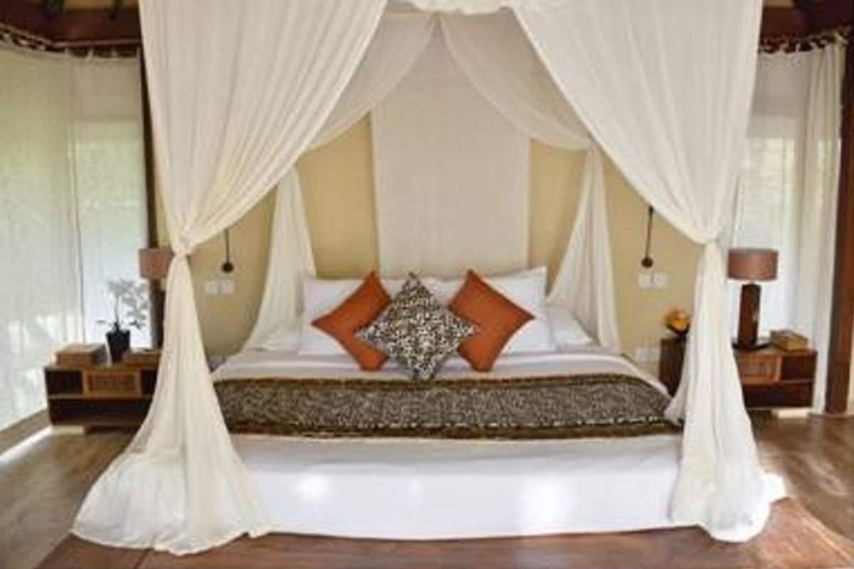 Ein Schlafzimmer mit Himmelbett, weißen Vorhängen und Holzboden.