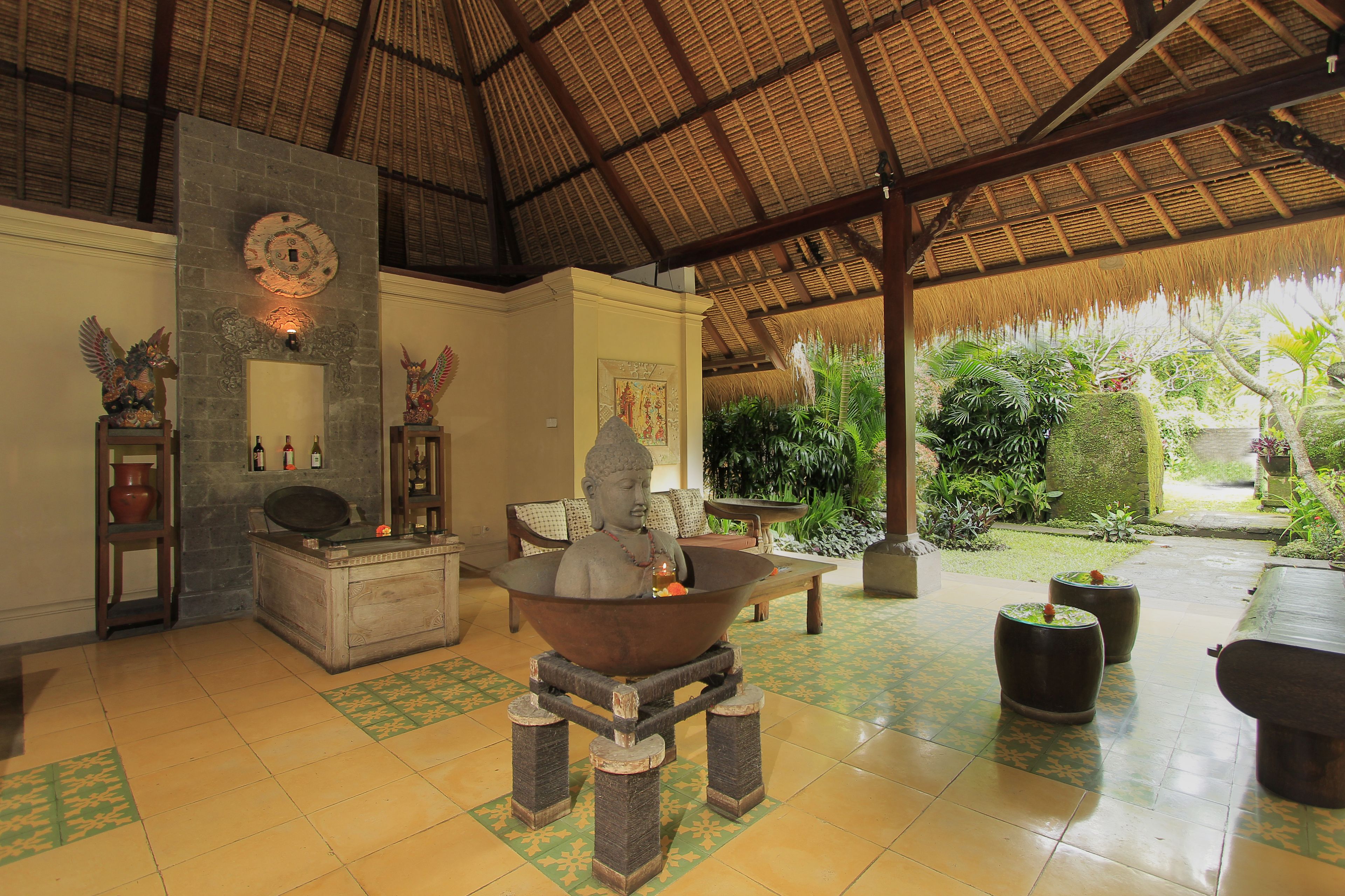 A traditional interior with a stone fireplace, wooden furniture, and a thatched roof.