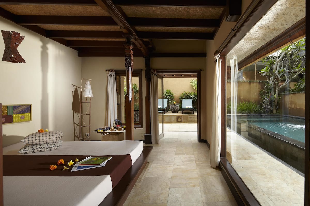 Une chambre d’hôtel avec un lit, une petite table avec une lampe et une vue sur une piscine.