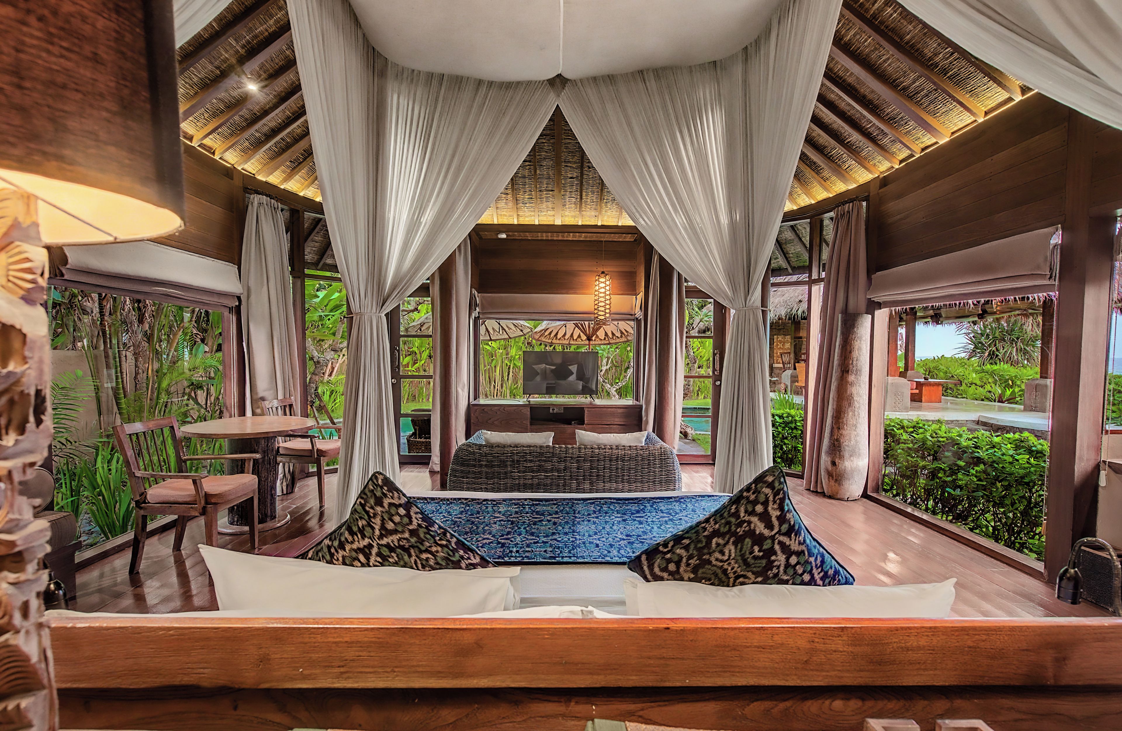 A room with a bed, a TV, and a view of a garden.